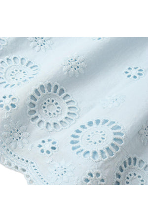 Light blue organic cotton fabric featuring intricate eyelet embroidery with floral designs. This delicate material showcases a soft, breathable texture, perfect for warm-weather clothing.