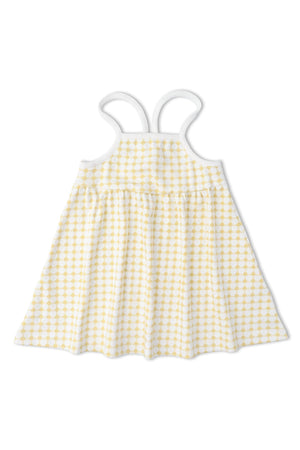 A light yellow and white dotty gingham dress featuring adjustable tie-back straps. Crafted from soft, breathable organic fabric, it’s perfect for warm-weather outings for young girls.