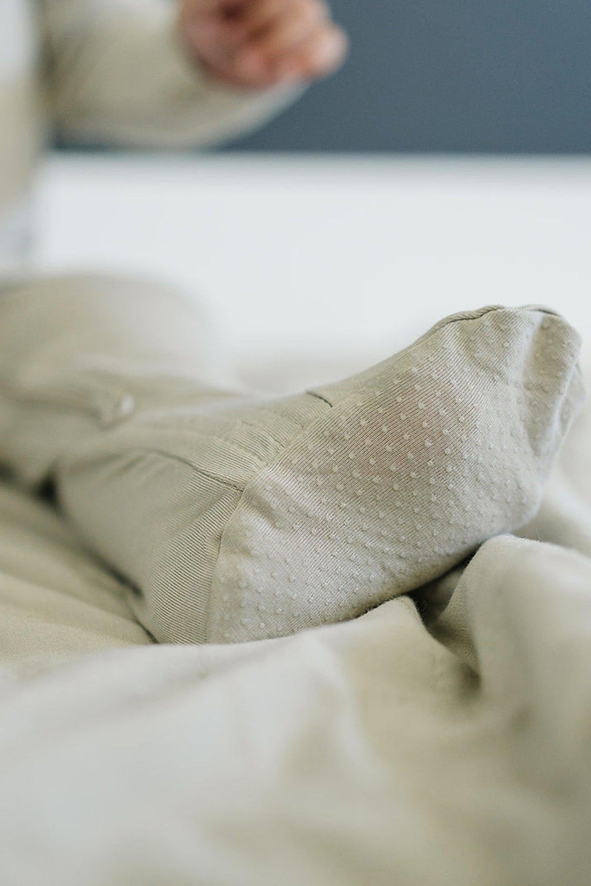 Close-up of a babys foot in beige bamboo footed pajamas, highlighting the soft fabric and texture.