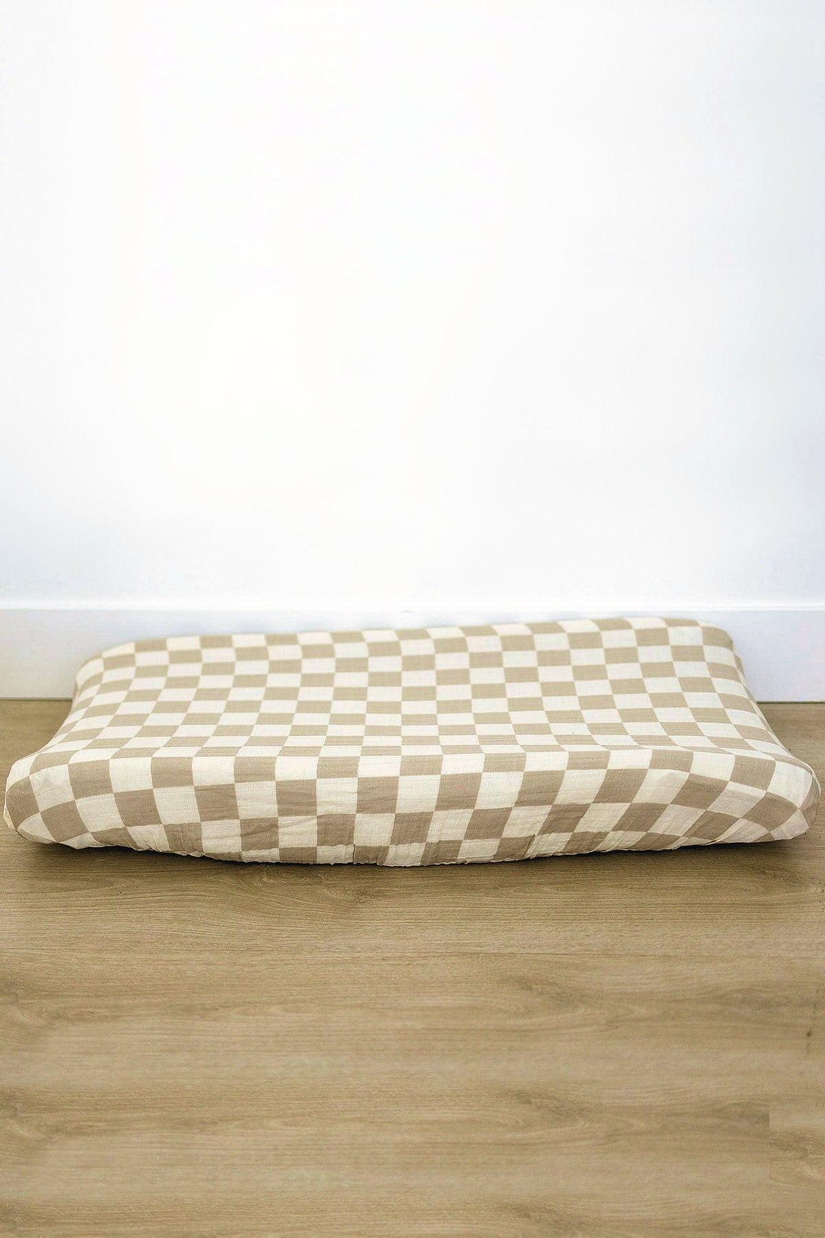 Taupe checkered muslin changing pad cover displayed on a flat surface, showcasing its soft, breathable cotton material. Ideal for adding style to any nursery while ensuring comfort for babies.