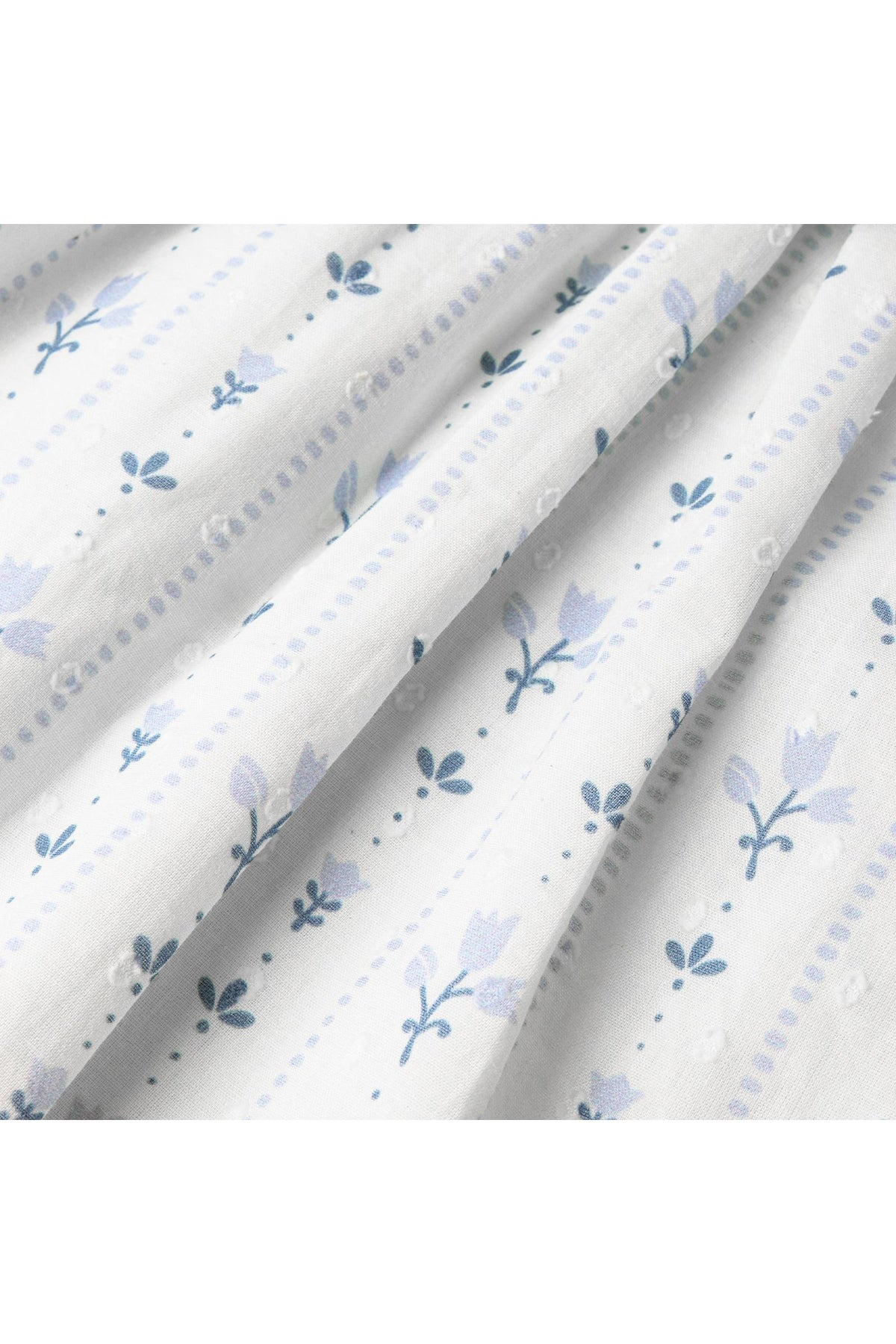 Close-up of soft, lightweight fabric featuring a delicate floral pattern in blue and gray tones, perfect for a breezy, organic childrens outfit. Ideal for sunny day outings.