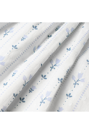 Close-up of soft, lightweight fabric featuring a delicate floral pattern in blue and gray tones, perfect for a breezy, organic childrens outfit. Ideal for sunny day outings.