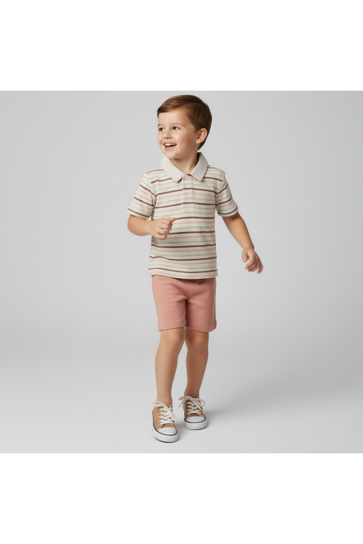 A young boy wears a striped collar tee in earthy tones and pink shorts, showcasing a playful style.
