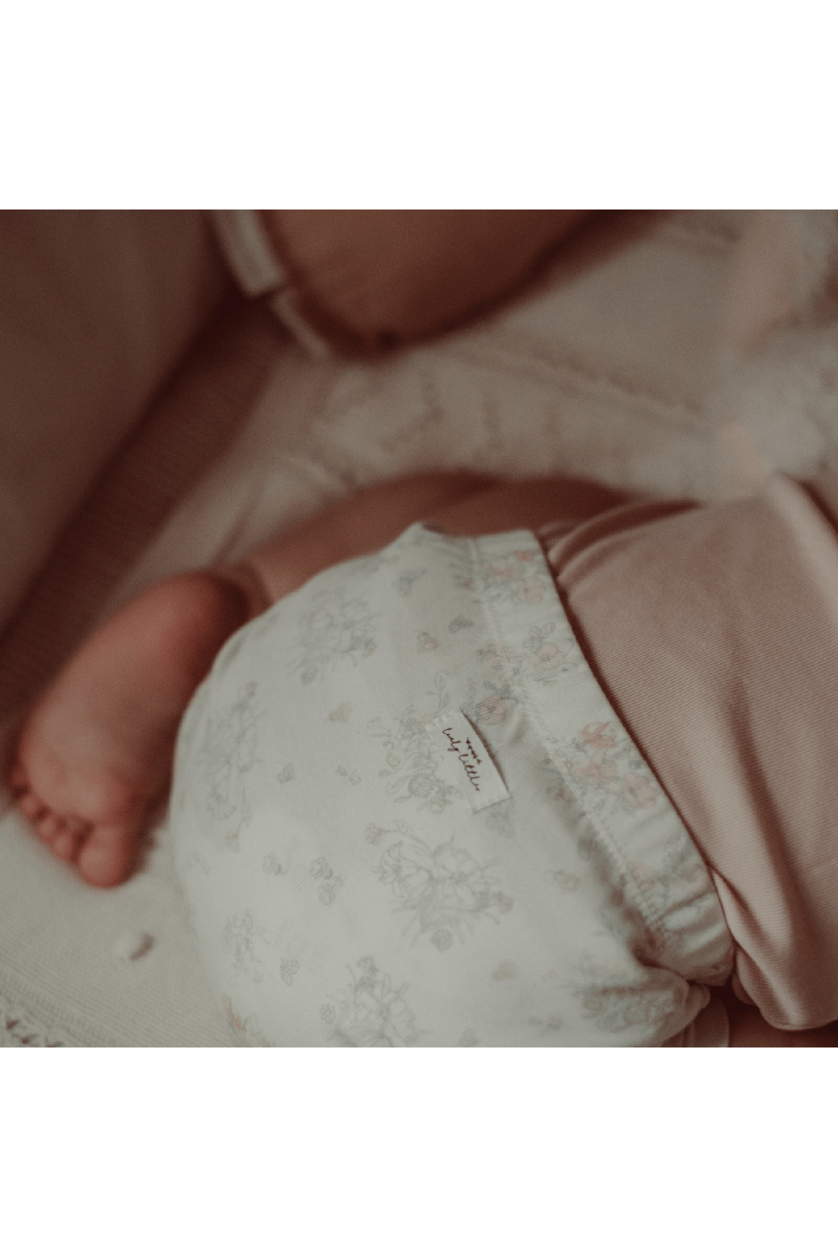 A close-up of a babys bottom in a floral cotton romper, featuring soft pastel colors and an elastic waistband.