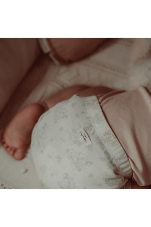 A close-up of a babys bottom in a floral cotton romper, featuring soft pastel colors and an elastic waistband.