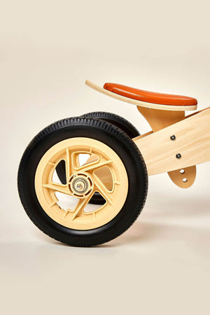 Close-up of a wooden balance bike wheel featuring a light-colored wooden frame and a sturdy black tire, highlighting the bikes sustainable design suitable for toddlers aged 2 to 4.