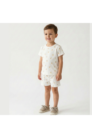 A young boy stands wearing a playful organic cotton tee and shorts set featuring a lemon print.