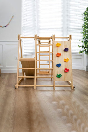 Wooden jungle gym for toddlers with climbing wall and slide, set in a bright, airy room.