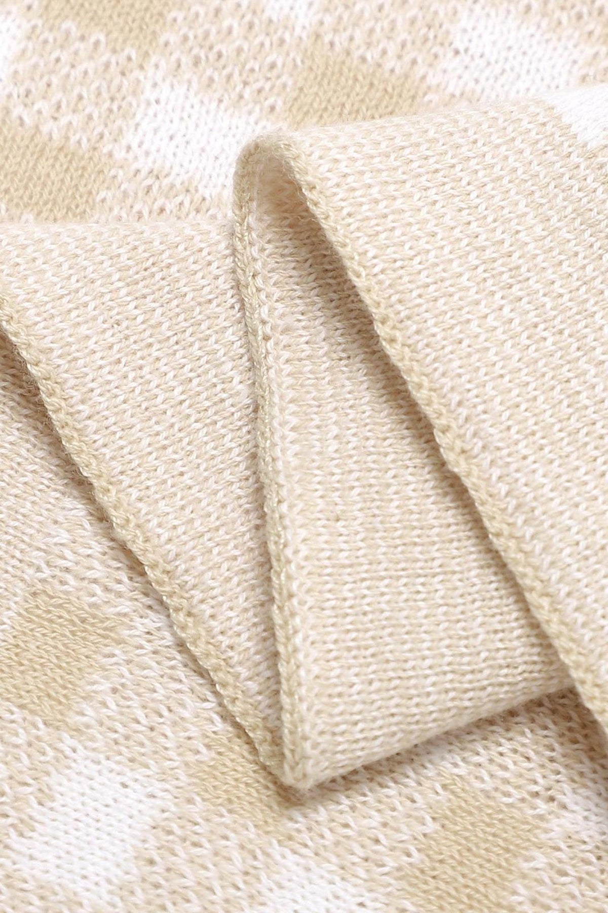 A close-up of a beige and cream checkered knit fabric, showcasing its soft, textured weave.