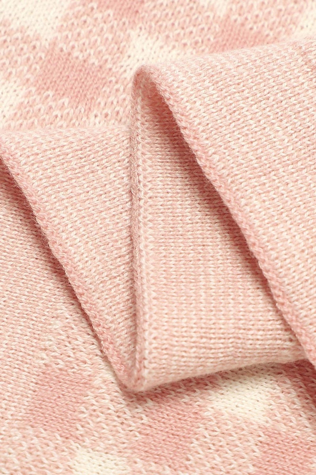 Close-up of a pink and white checkered knit blanket, showcasing its soft texture and intricate pattern.
