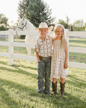 Two children, a boy in a western-style shirt and a girl in a floral dress.
