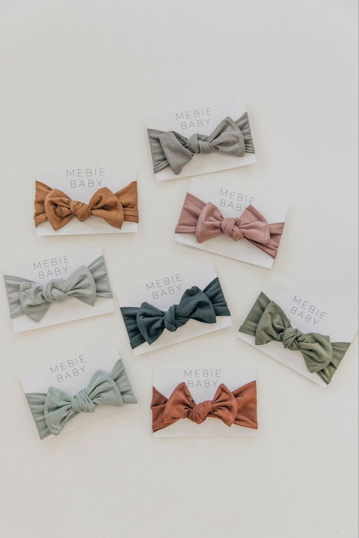 Assorted Mebie Baby head wraps in various earthy tones displayed on white cards on a light background.