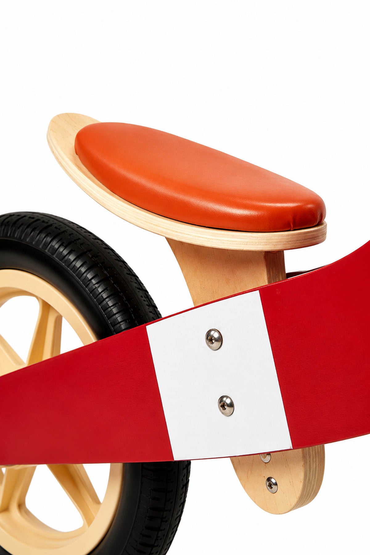 Close-up view of a wooden balance bike featuring a red frame, a natural wood seat, and a brown leather seat cover.