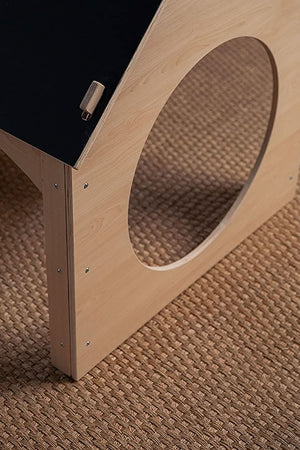 A close-up view of a wooden childrens playhouse featuring a chalkboard roof, set on a textured, woven rug. The natural wood finish highlights its eco-friendly design and playful aesthetic.