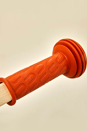 Close-up of a textured, orange rubber handle featuring grooves, attached to a wooden frame. This component appears to enhance grip and comfort for young children using the balance bike.