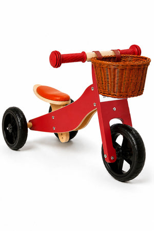 A colorful wooden balance bike features a red frame, black wheels, and an orange seat.