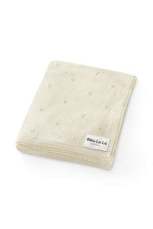 Cream-colored knit swaddle blanket with a subtle pointelle pattern and Bleu La La Organics label on the corner.