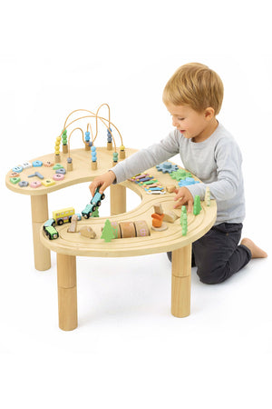A young child plays at a wooden multi-activity sensory table featuring colorful gears, a bead maze, and miniature vehicles.