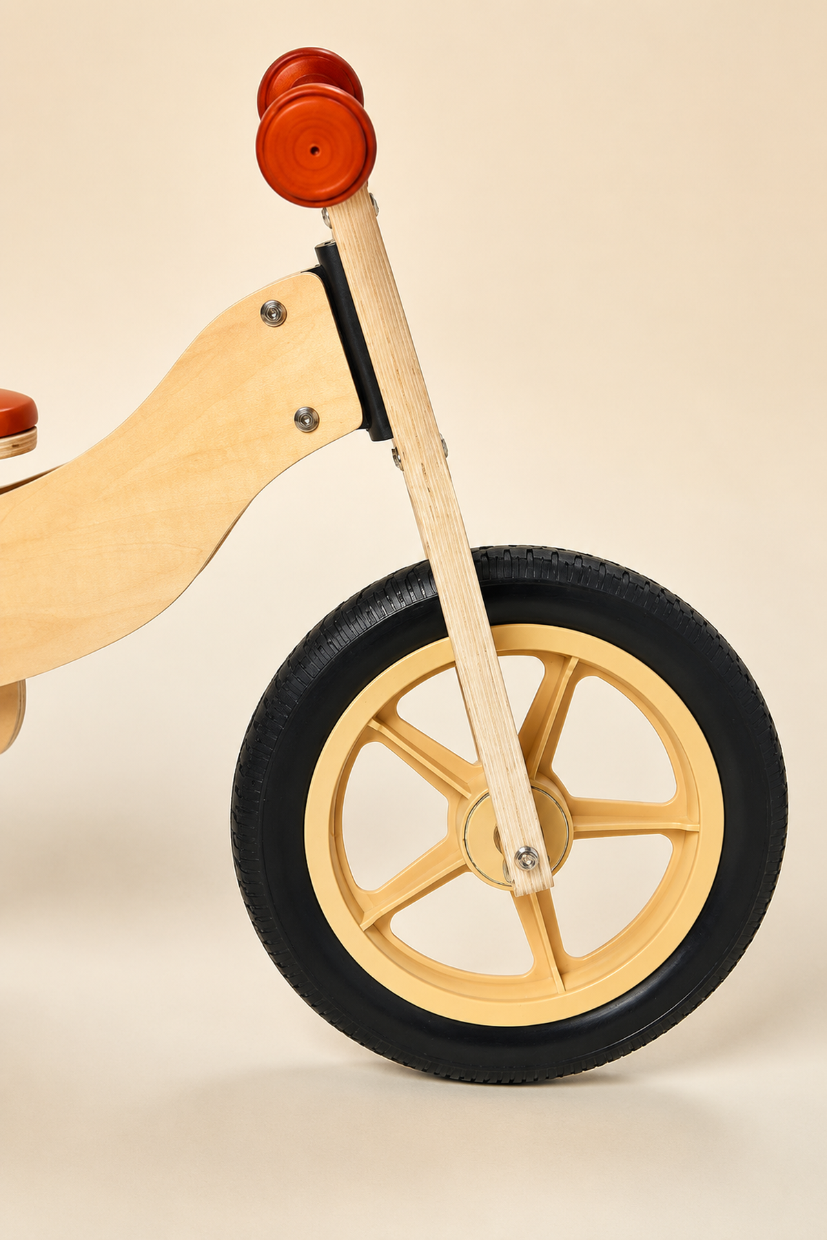 A close-up of a wooden balance bikes front wheel features a natural wood frame and a black rubber tire, showcasing its sturdy construction and eco-friendly design for toddlers aged 2.