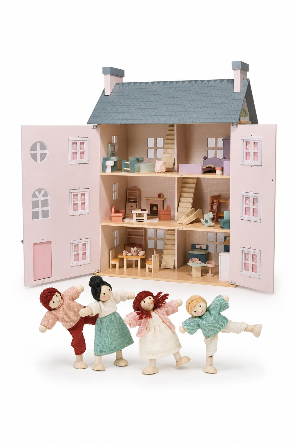 A pastel pink dollhouse with four levels features wooden furniture and a cozy interior. Four fabric dolls stand in front, ready for imaginative play in this charming, eco-friendly set.