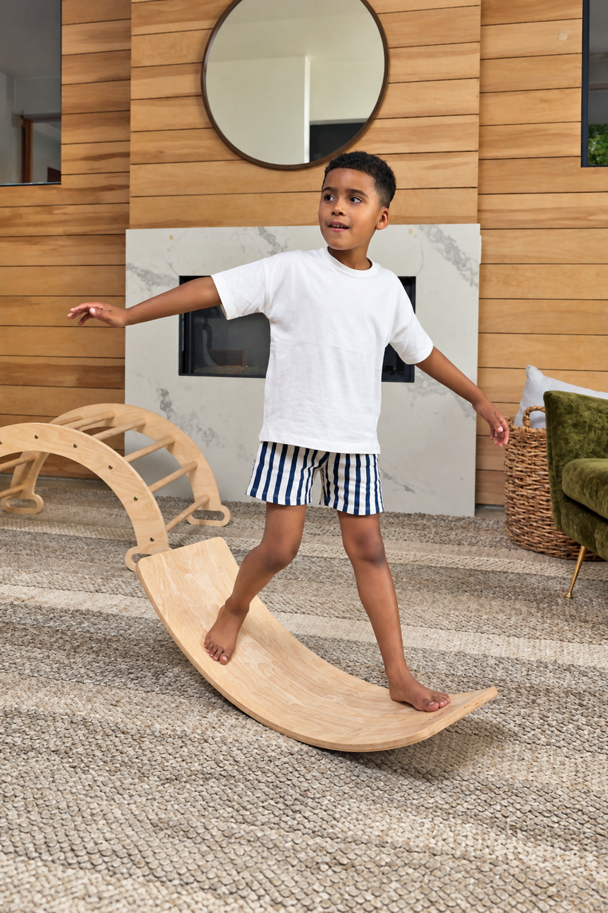 A child balances on a wooden curved balance board in a stylish, modern living room. The setting features a fireplace and natural elements, promoting active play and imagination.