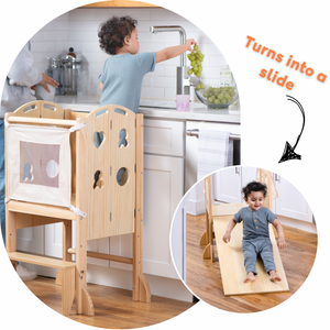 A toddler reaches for grapes while standing in a wooden kitchen tower, designed for versatile use. The tower features a mesh panel and can transform into a slide for playtime.