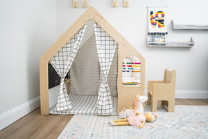 A wooden playhouse with a black-and-white grid pattern features an open front and colorful abacus. Nearby, a small chair and plush toys are arranged on a soft area rug.