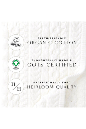 Close-up of a soft white fabric featuring a classic cable knit pattern, labeled with eco-friendly attributes like organic cotton and GOTS certification, emphasizing heirloom quality and sustainability.