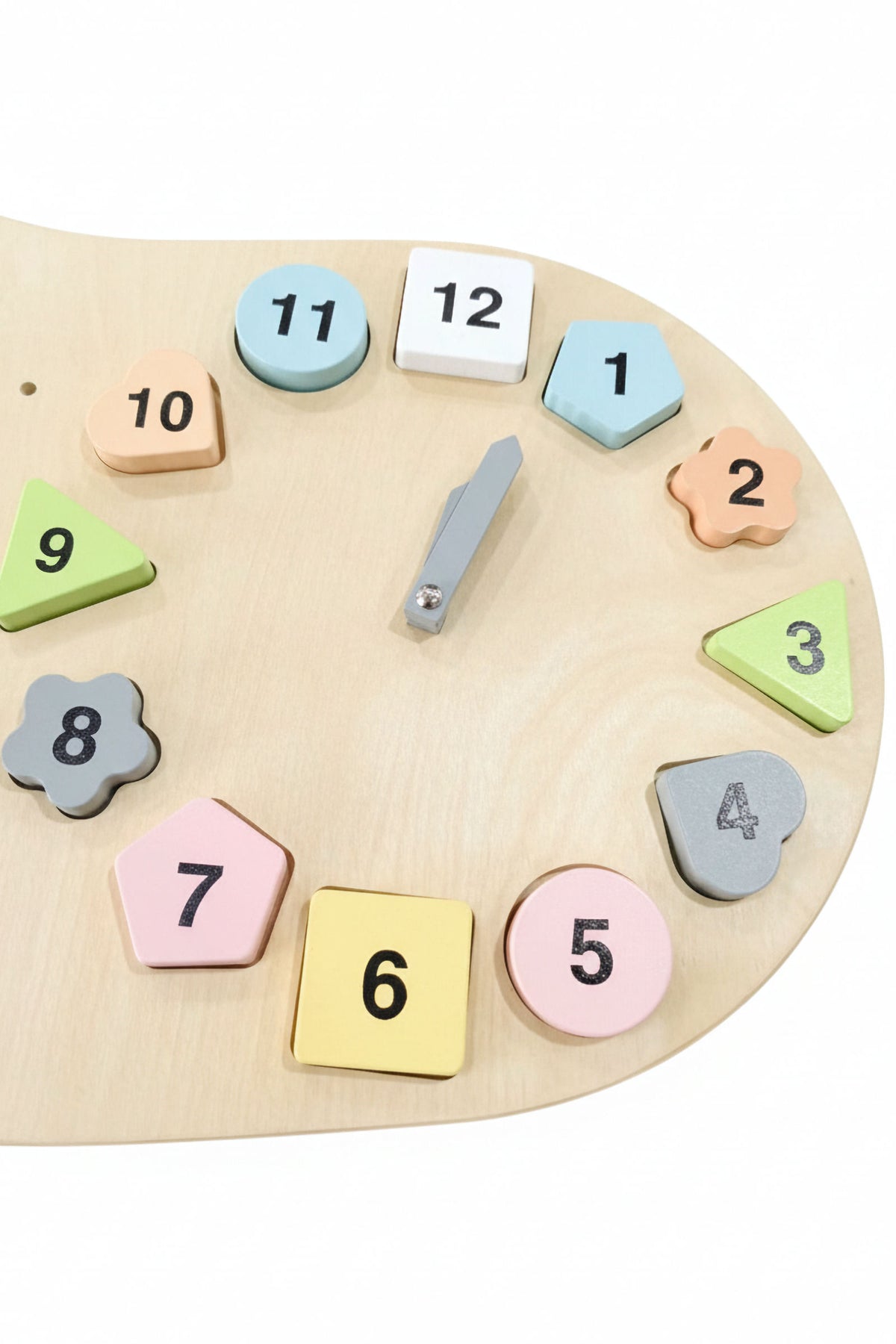 Colorful wooden shapes with numbers surround a gray clock hand on a light wooden surface, promoting learning through play.