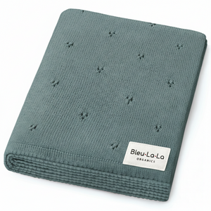 A soft, textured teal blanket made from 100% organic cotton, featuring a pointelle knit design. The blanket is neatly folded, showcasing its gentle, breathable fabric ideal for babies.