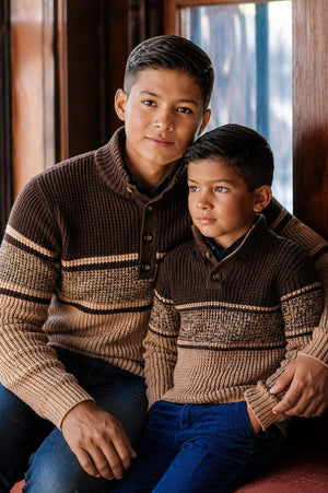 A young boy and his father sit together wearing matching organic cotton waffle sweaters in earthy tones.