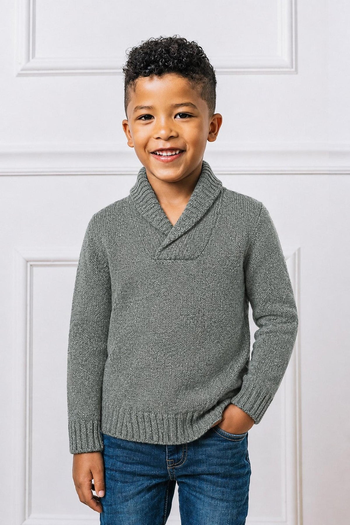 A smiling boy wears a gray shawl collar sweater made from soft, organic cotton, paired with blue jeans. The cozy design is perfect for casual outings and family gatherings.