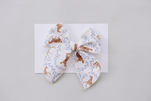 A handcrafted fabric hair bow featuring a charming pony print in earthy tones, set against a white background. Ideal for babies and kids, it combines style and comfort.