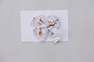 A charming Western pony print hair bow in soft cotton fabric features a light background with horse illustrations and delicate foliage.