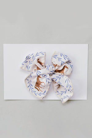A charming Western pony print hair bow in white and gold, crafted from soft fabric with a delicate fringe. Perfect for babies and kids, adding style to any outfit.