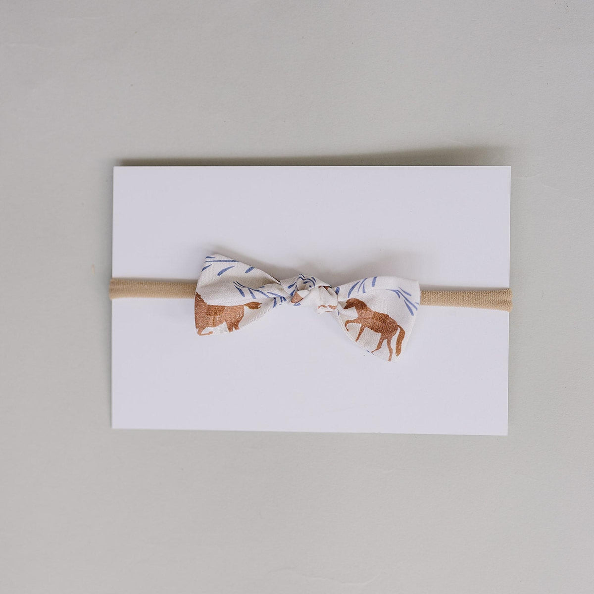 Handcrafted Western pony print hair bow in soft cotton fabric, featuring a neutral tan elastic band. Ideal for babies and kids, adding charm to any outfit.