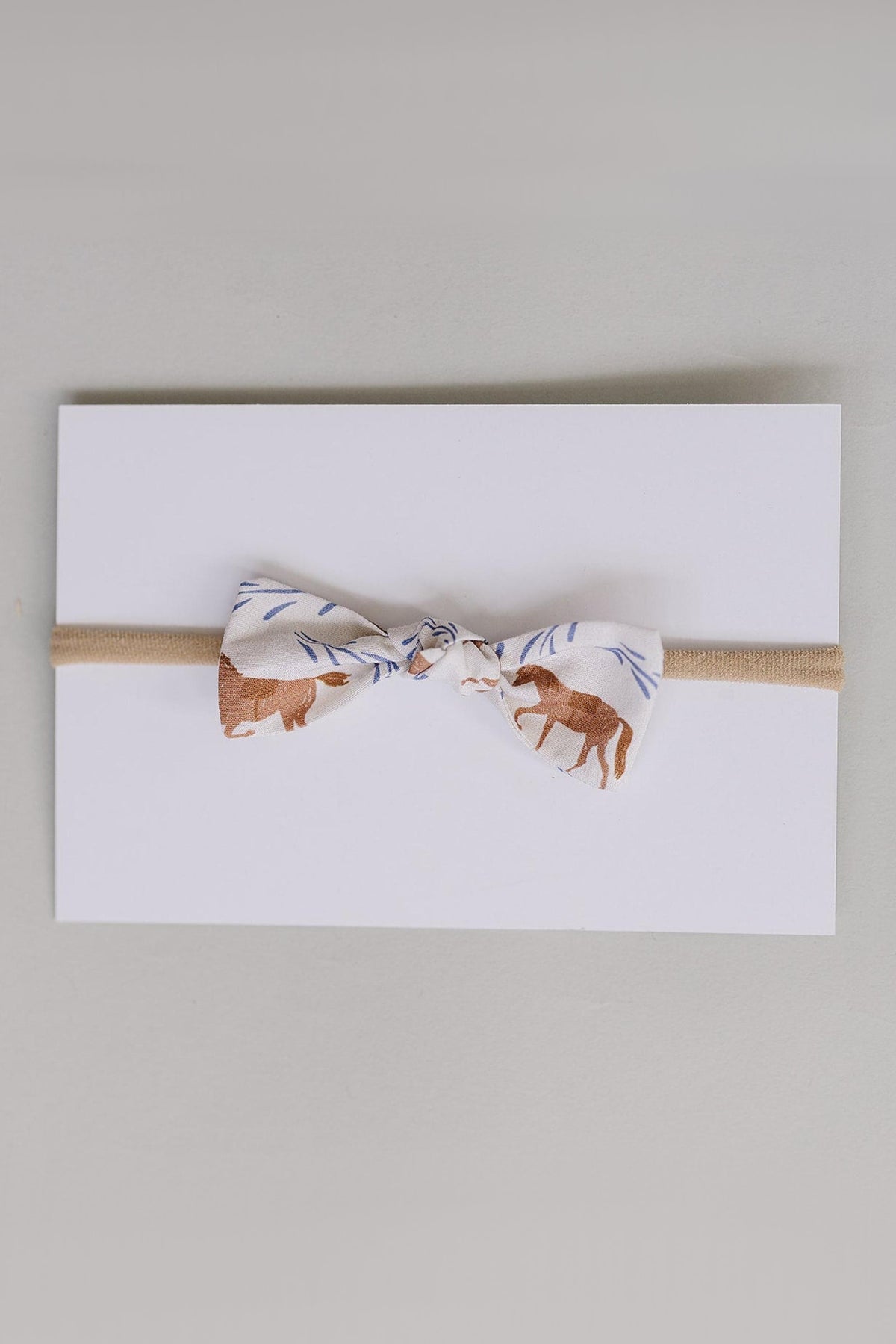 A handcrafted hair bow featuring a western pony print in earthy tones, mounted on a light card.