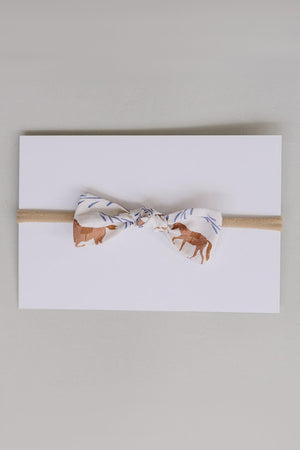 A handcrafted hair bow featuring a western pony print in earthy tones, mounted on a light card.