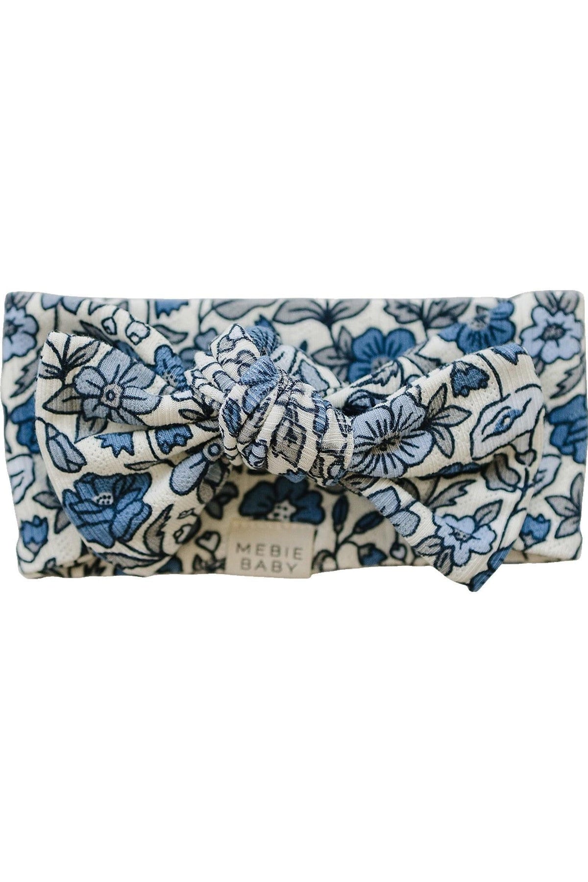 Blue and white floral baby head wrap with a knotted bow, made from soft fabric. Features Mebie Baby label.