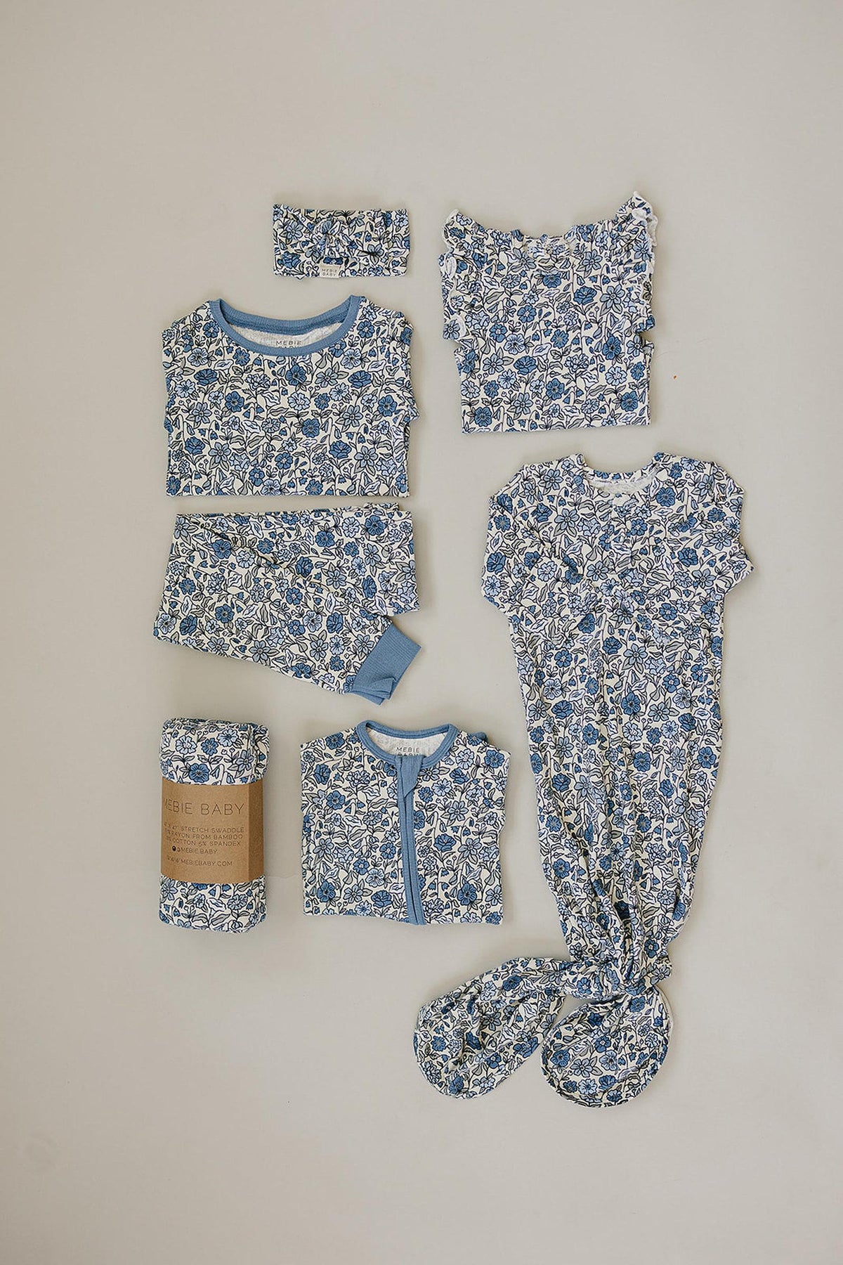 Blue floral baby clothing set includes a knotted gown, romper, and headband made from soft bamboo fabric.