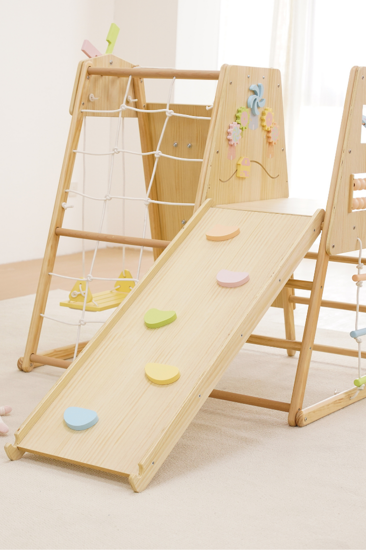 A wooden indoor climbing playset features a smooth slide with colorful grips and a climbing frame adorned with playful decorations. The natural wood finish enhances its eco-friendly appeal for toddlers.