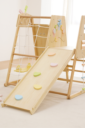 A wooden indoor climbing playset features a smooth slide with colorful grips and a climbing frame adorned with playful decorations. The natural wood finish enhances its eco-friendly appeal for toddlers.