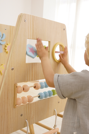 A child interacts with a wooden play gym featuring colorful shapes and an abacus. The natural wood finish and safe design encourage imaginative play and skill development for toddlers.