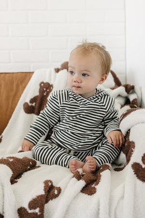 A baby sits comfortably on a cozy couch covered with a soft, bear-patterned blanket, wearing a charcoal stripe ribbed hooded set made from breathable fabric.