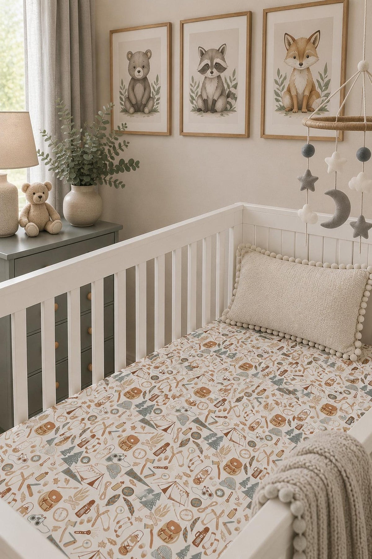 A cozy nursery features a white crib with a fitted sheet displaying a whimsical nature print. Soft teddy bears and decorative animal artwork add charm to the serene setting.