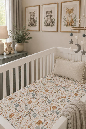 A cozy nursery features a white crib with a fitted sheet displaying a whimsical nature print. Soft teddy bears and decorative animal artwork add charm to the serene setting.