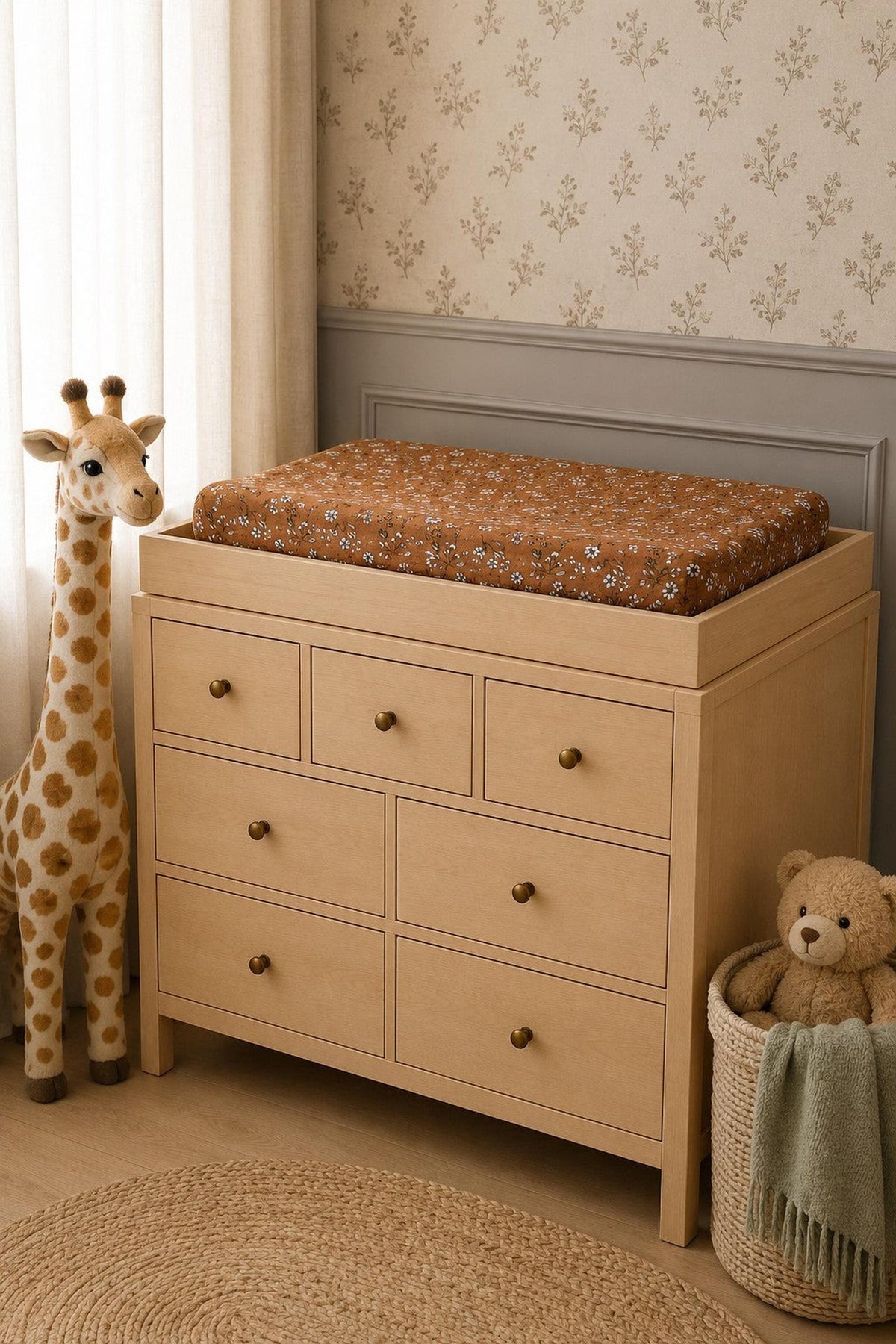 A wooden changing table with drawers features a vintage floral muslin changing pad in warm brown tones.