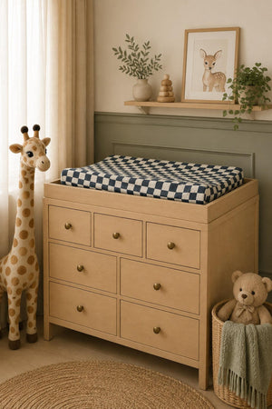 A cozy nursery scene features a wooden changing table with a charcoal checkered muslin changing pad cover.