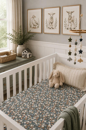 A cozy nursery scene featuring a white crib with a Midnight Floral muslin crib sheet adorned with delicate floral patterns. Soft toys and decorative art enhance the inviting atmosphere.