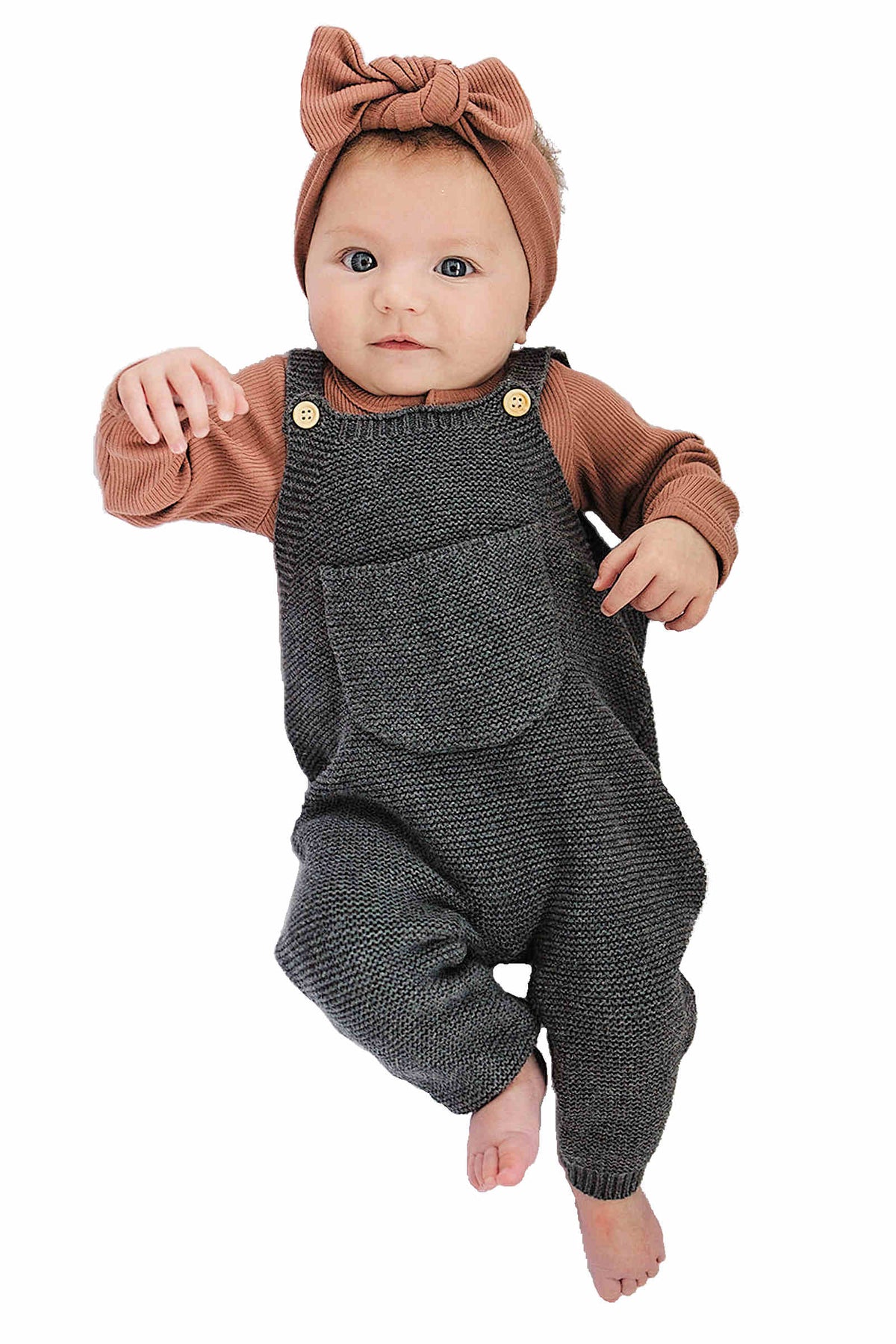 A baby in a dusty rose ribbed long sleeve bodysuit and knitted gray overalls, with a matching headband.
